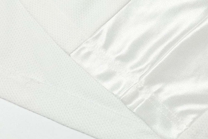 Close-up of a white mesh football jersey with satin sleeve detail and textured fabric stitching