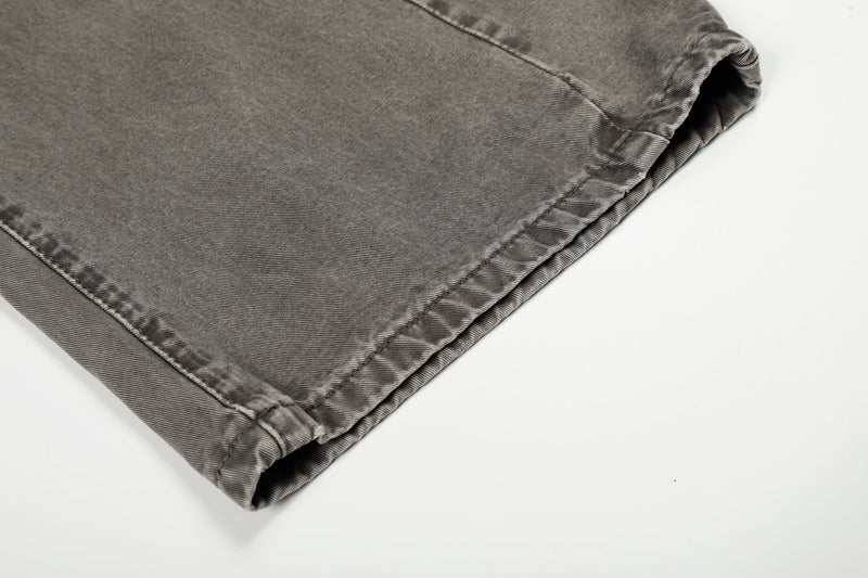 Close-up of hem on grey washed denim jeans showing wide cuff and stitched edge