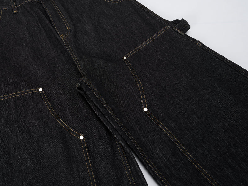 Upper front of dark wash carpenter pants showing front pockets and utility side pocket details