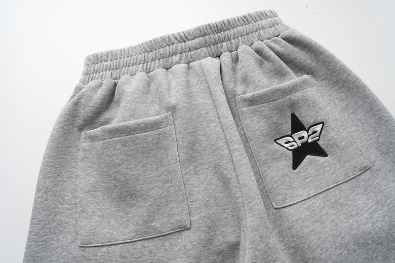 Back view of gray sweat shorts with two patch pockets and star logo on one pocket
