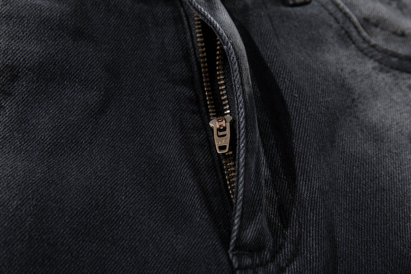 Close-up of the front zipper on dark washed jeans with bronze YKK zipper teeth