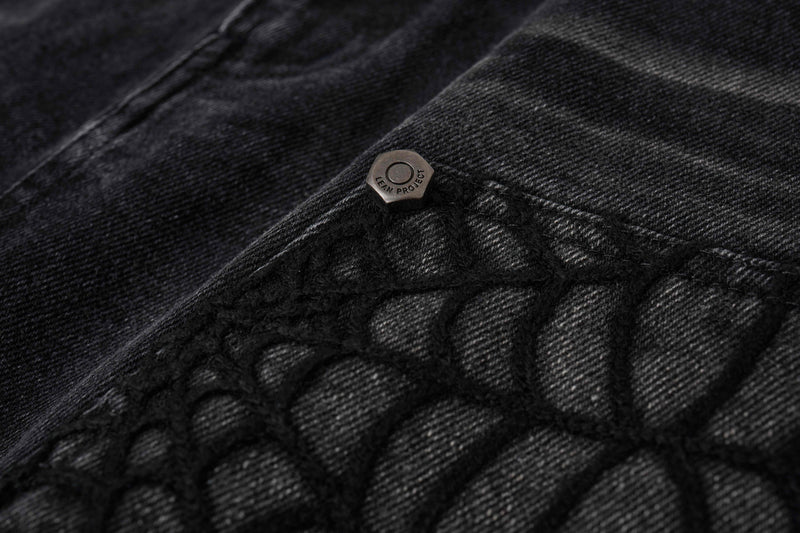 Close-up of black denim shorts spiderweb pocket corner with branded snap button
