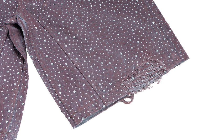 Close-up of frayed hem on dark brown denim shorts with rhinestone embellishments