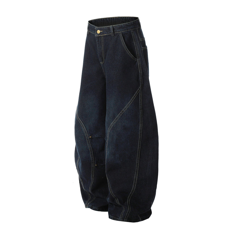 Angled front view of dark wash wide-leg denim pants with curved seam detailing and brass button waist