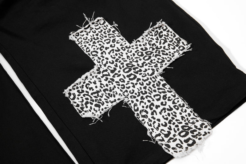 Frayed leopard-print cross patch on black cargo pants leg close-up
