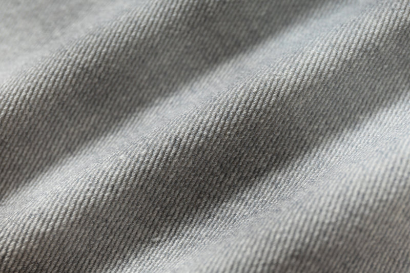 Close-up of light wash denim fabric texture with soft diagonal folds