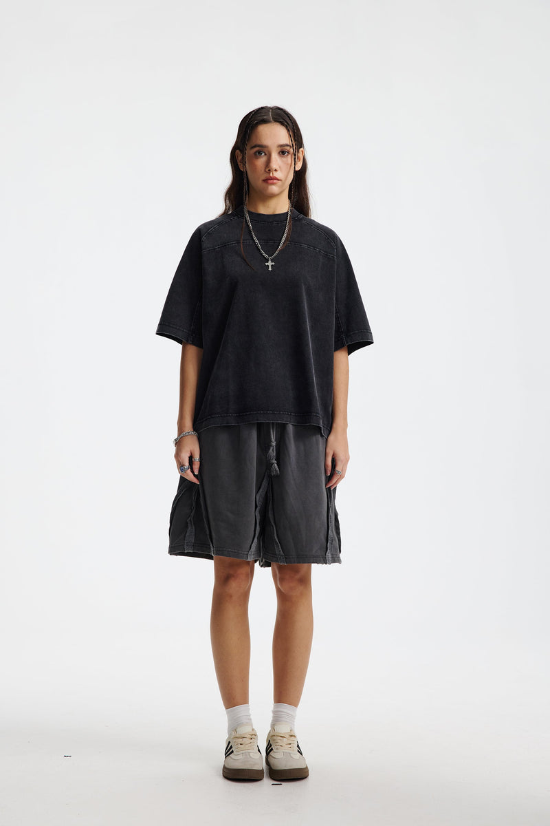 Model wearing a vintage washed oversized black cotton T-shirt styled with streetwear shorts and sneakers