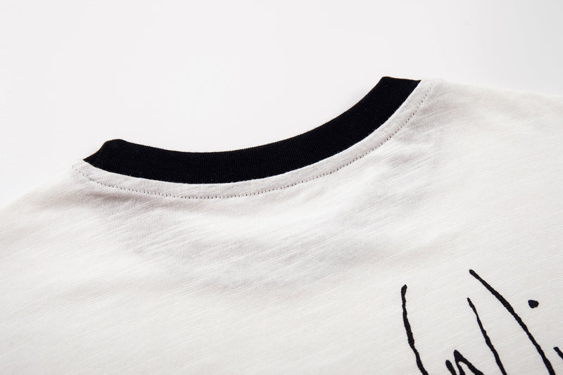Close-up of a white graphic T-shirt with black ribbed collar and abstract horse design detail