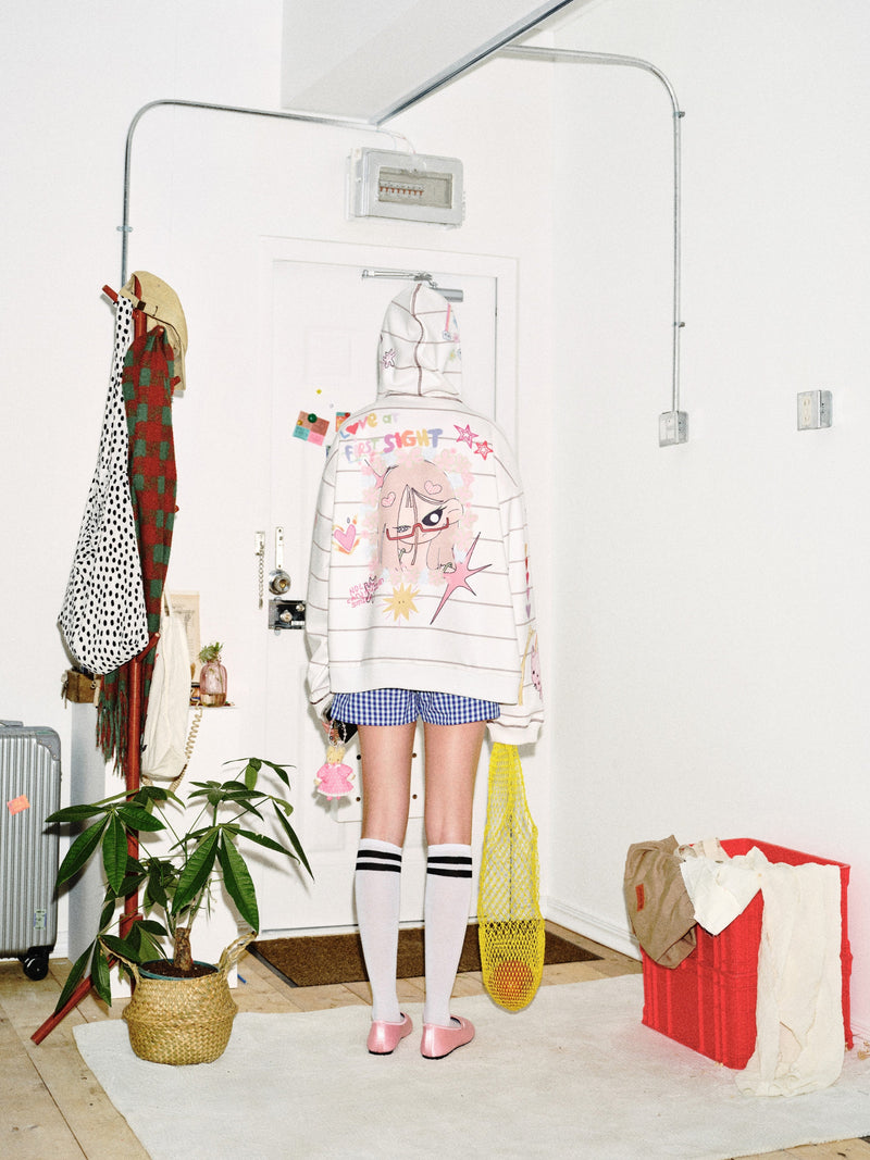 Back view of model wearing cream zip-up hoodie with large cartoon graphic on the back