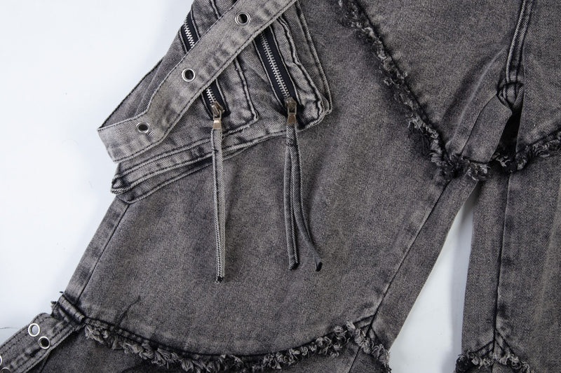 Side front close-up of washed black jeans with zipper pocket and hanging strap cords