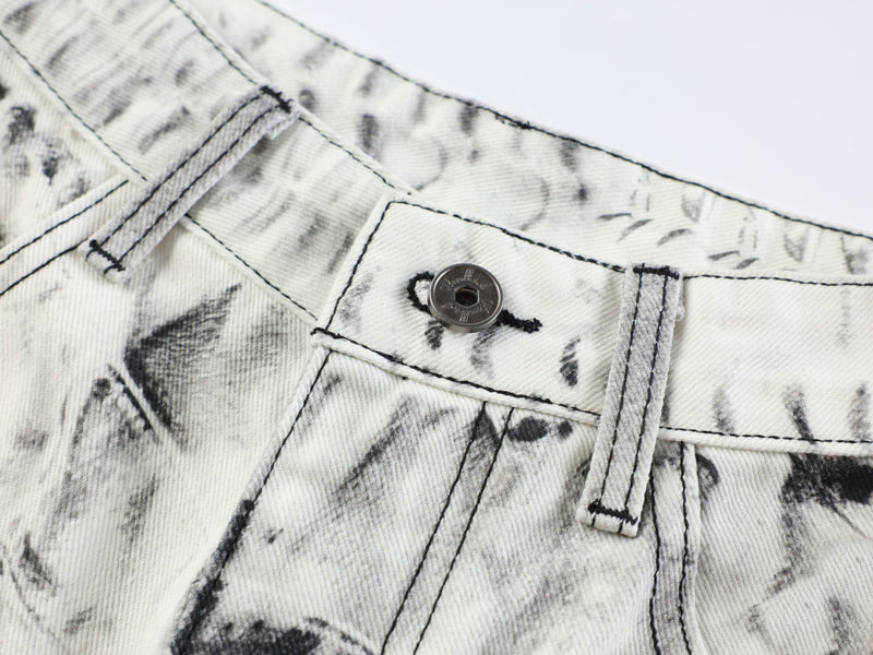 Close-up of front button and top seam on white and black distressed denim