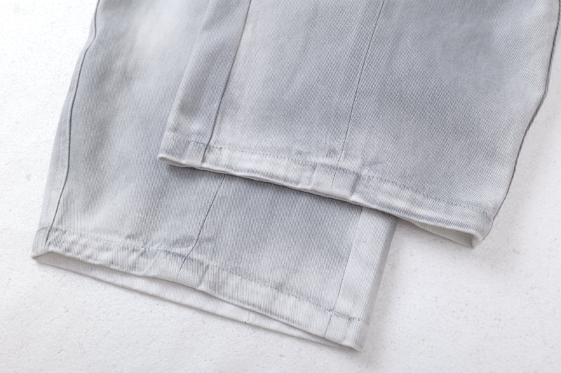 Close-up of the wide hem on light gray washed jeans with visible topstitching