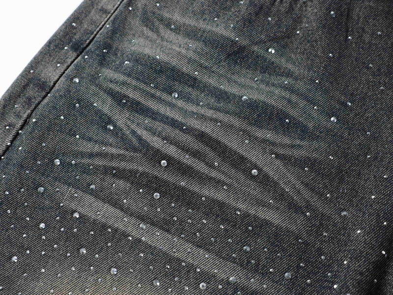 Close-up of black denim fabric with rhinestone embellishments and faded diagonal wash