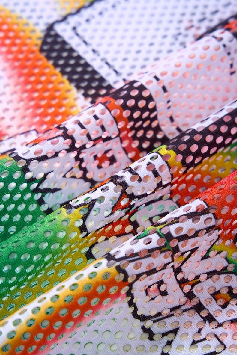 Close-up of multicolor gradient mesh jersey fabric with perforated texture and abstract black line pattern