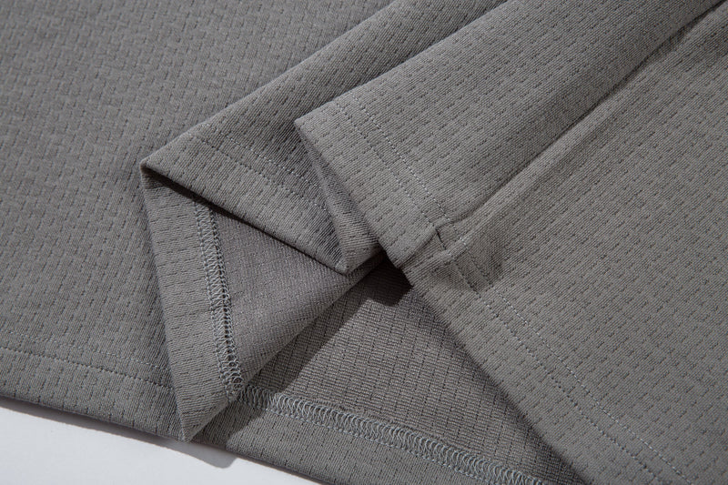 Close-up of gray sleeve and hem seam showing textured mesh fabric