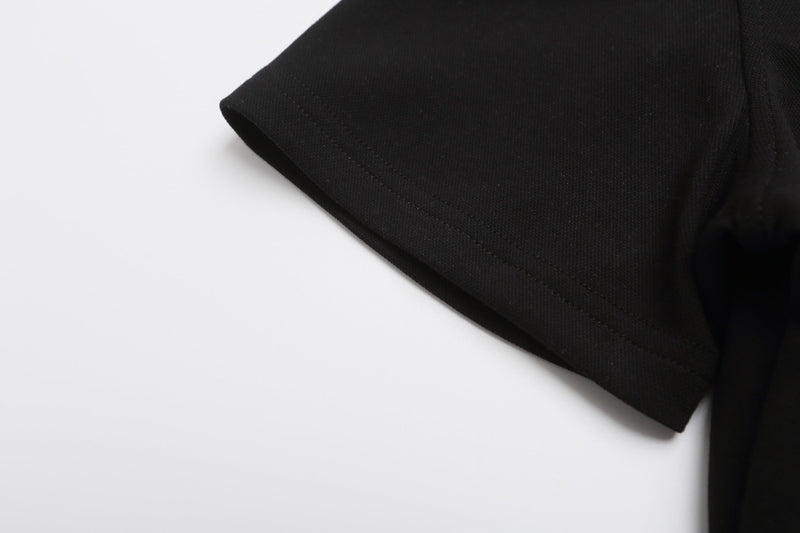 Close-up of a black polo shirt sleeve with double stitching and textured fabric detail on a white background