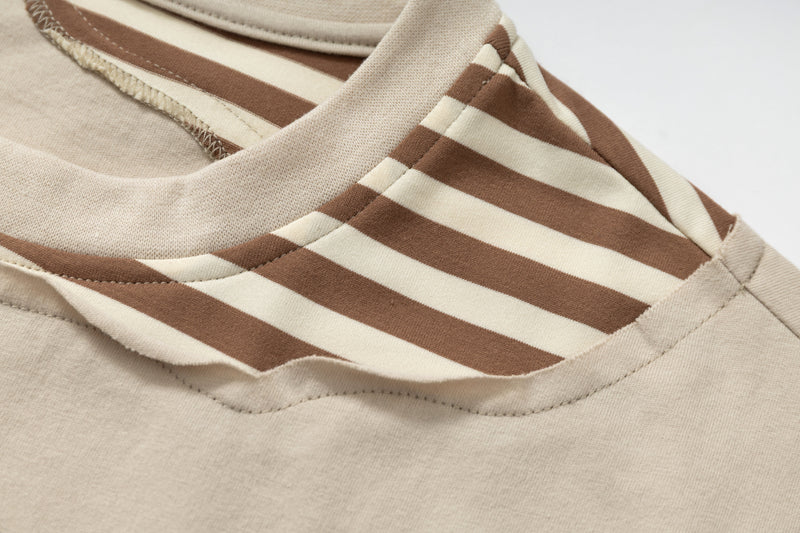 Close-up of a beige layered graphic tee with brown and cream striped collar detail and visible stitching