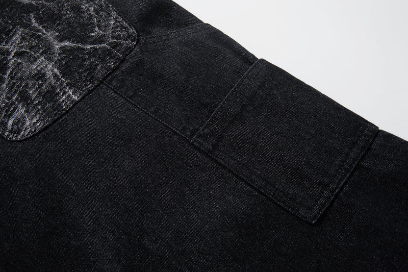 Close-up of black denim leg seam with cracked panel fabric near the upper thigh