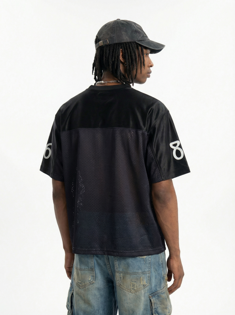 Black mesh jersey with oversized 89 on the sleeves, styled on a model with distressed jeans and cap