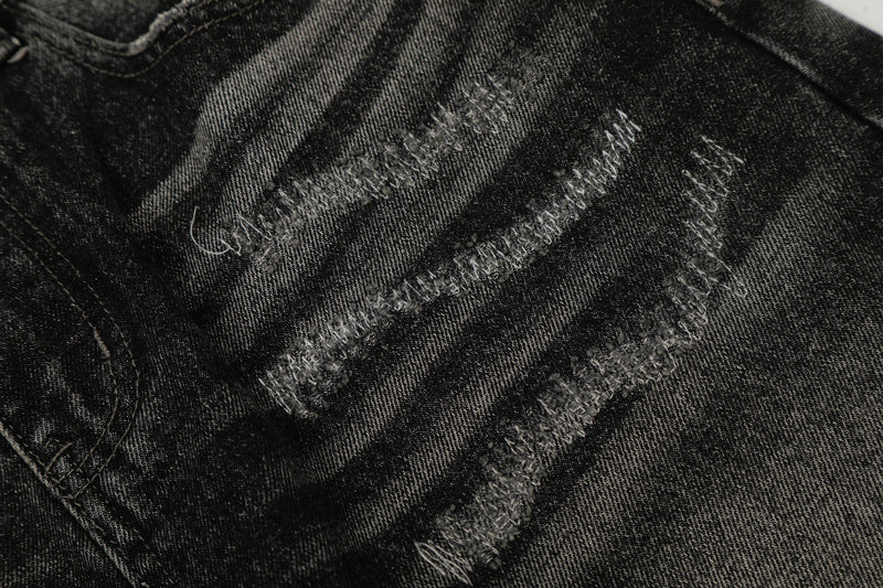 Close-up of stitched distressed details on black washed denim fabric