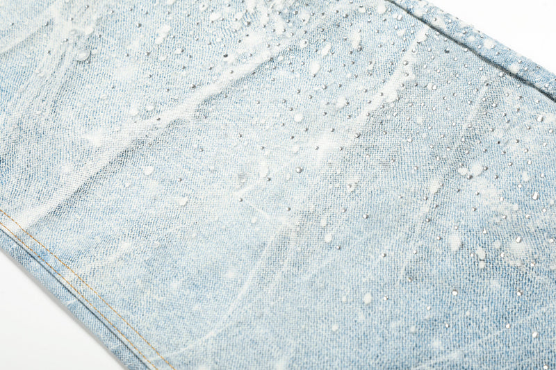 Close-up of jean leg with pale blue denim, white spiderweb wash, and scattered speckled dots