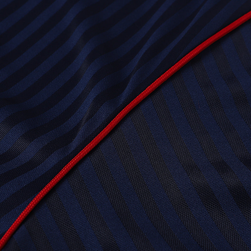 Close-up of navy soccer jersey fabric with diagonal ribbing and a bright red trim seam