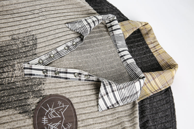 Close-up of layered sweater collar with plaid trim over beige and black knit panels