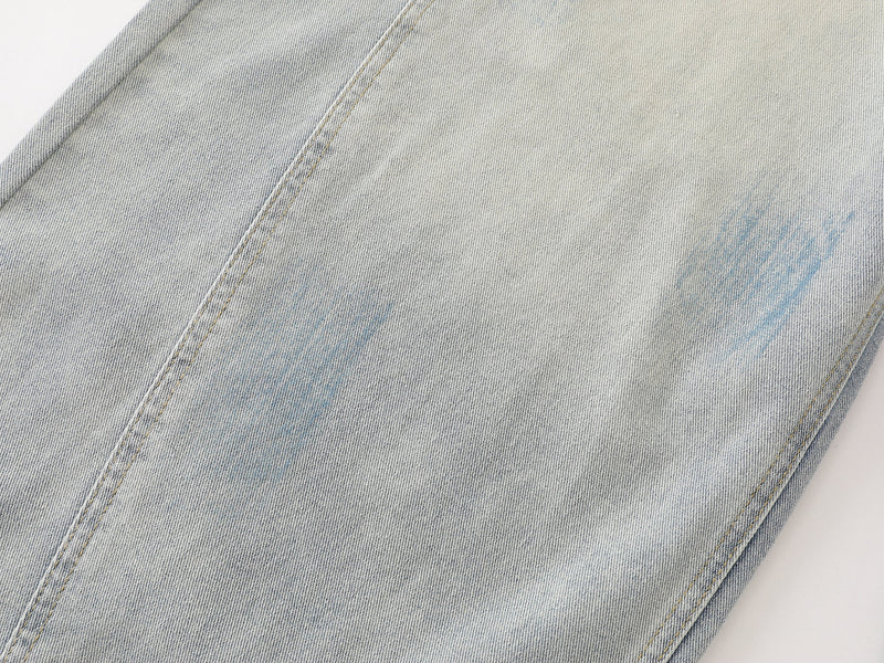 Close-up of light wash denim leg with subtle blue paint marks