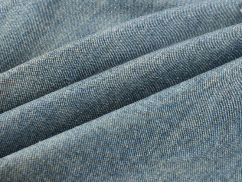 Close-up of light blue denim fabric with soft ribbed texture and faded wash