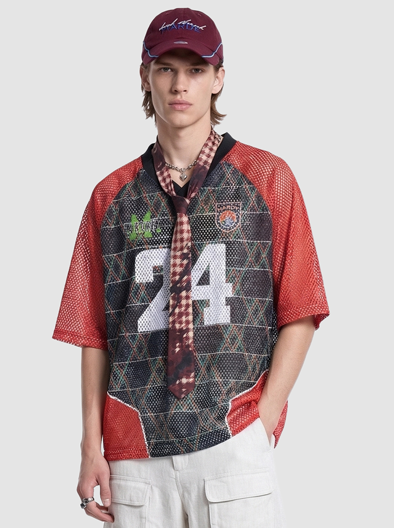 Model wearing a red and black mesh varsity jersey with number 24, graphic patches, and a maroon cap