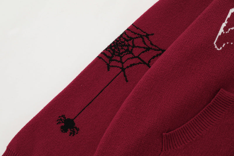 Close-up of burgundy sleeve with spiderweb knit and hanging spider detail