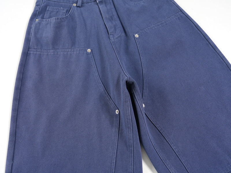 Blue jorts angled side view showing front and back pockets, rivets, and wide-leg shape