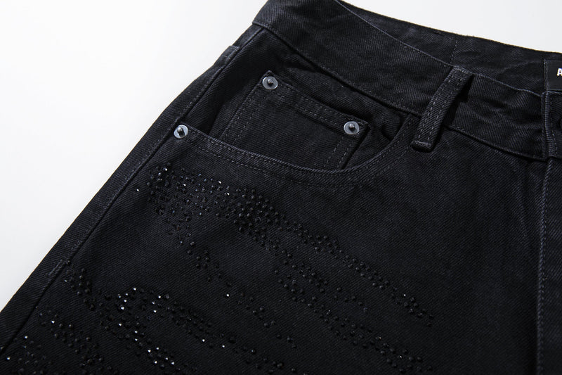 Close-up of the front pocket and rhinestone swirl detail on black denim jeans