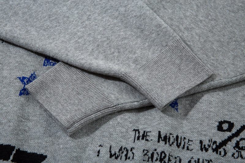 Close-up of ribbed gray sweater sleeve laid over the front graphic knit fabric
