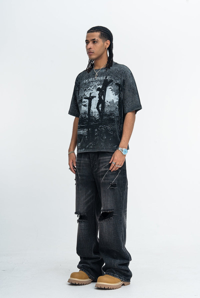 Model wearing a vintage washed black graphic tee with Doré Bible 1866 crucifixion print, paired with distressed jeans and tan boots
