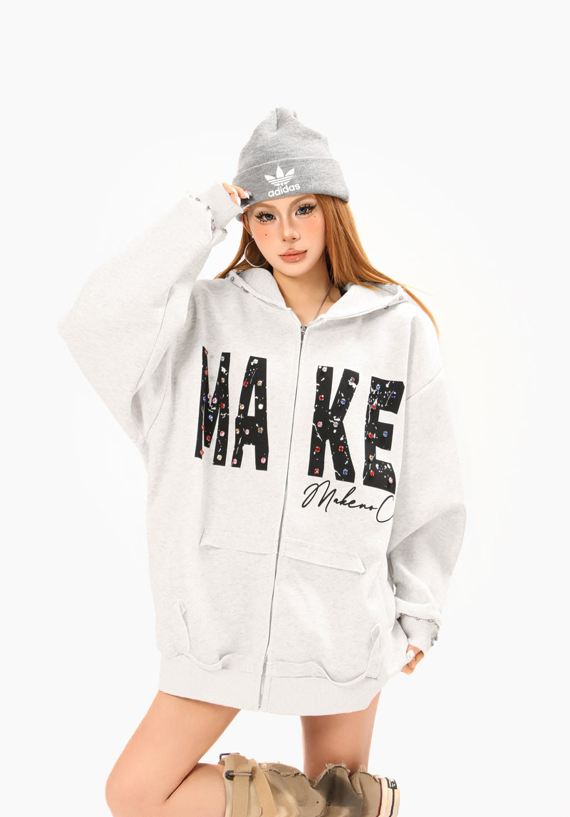 Light gray oversized zip hoodie worn by model with MAKE graphic and hood up