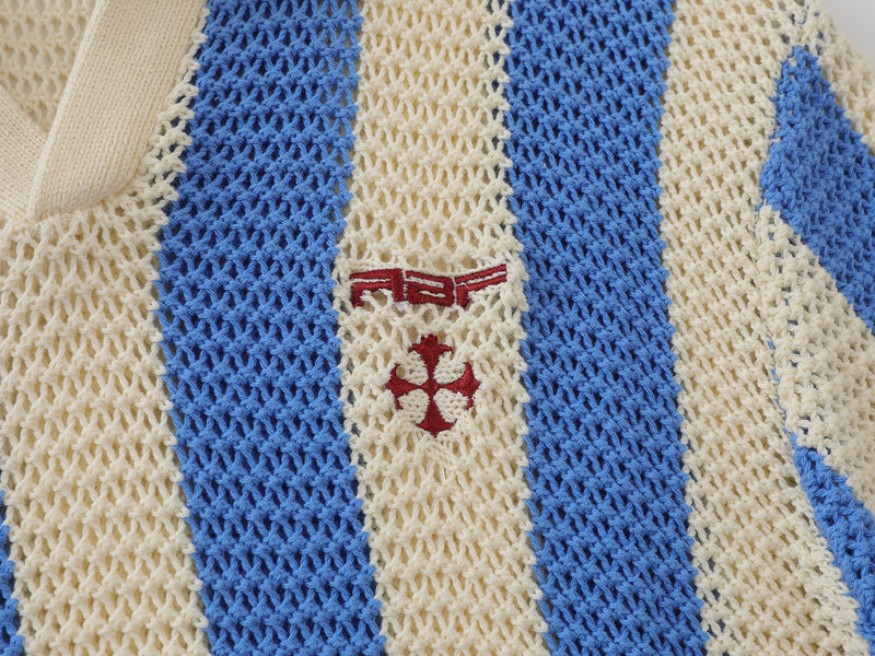 Close-up of blue and cream striped mesh knit sweater chest with red embroidered logo