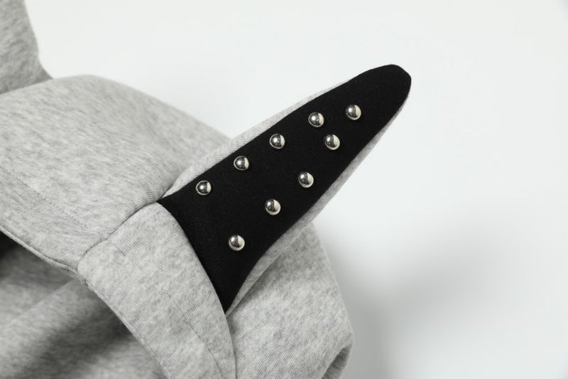 Close-up of one black devil horn on grey hoodie hood with metal studs