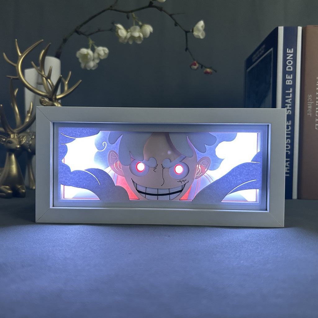 The Seakoff One Piece Anime Light Box, featuring Gear 5 Luffy with dynamic color-changing effects, includes a framed image of a mischievous animated character with glowing red eyes, surrounded by decorative elements like a deer figurine and white flowers that capture its whimsical charm.