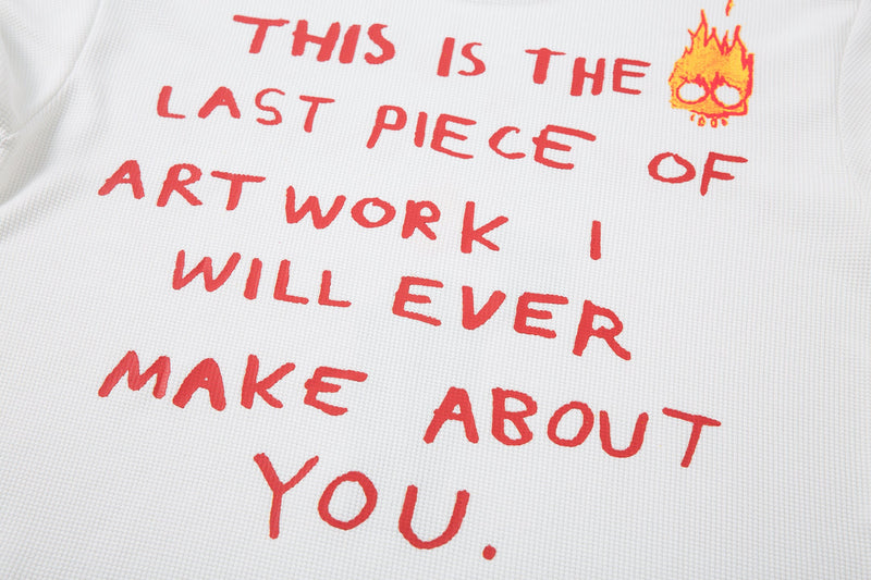 Back graphic close-up on white tee with red text and flame doodle near the shoulder