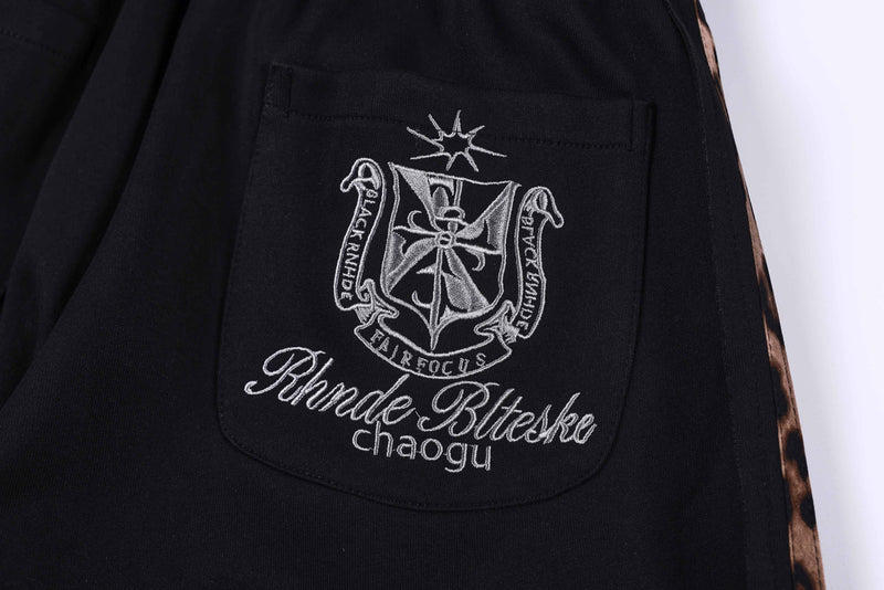 Back pocket close-up on black shorts with embroidered crest and script text