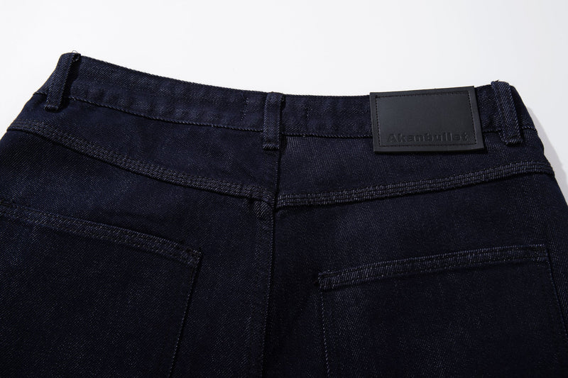 Back waistband of dark wash jeans with black logo patch and belt loops