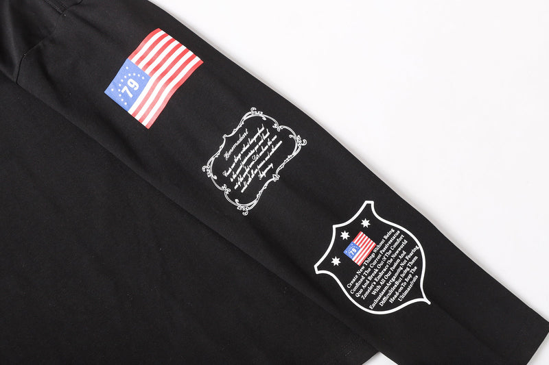 Black sleeve laid flat showing flag graphic, decorative text block, and shield print near the cuff