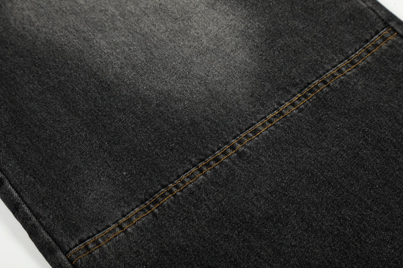 Close-up of black washed denim leg with diagonal topstitching
