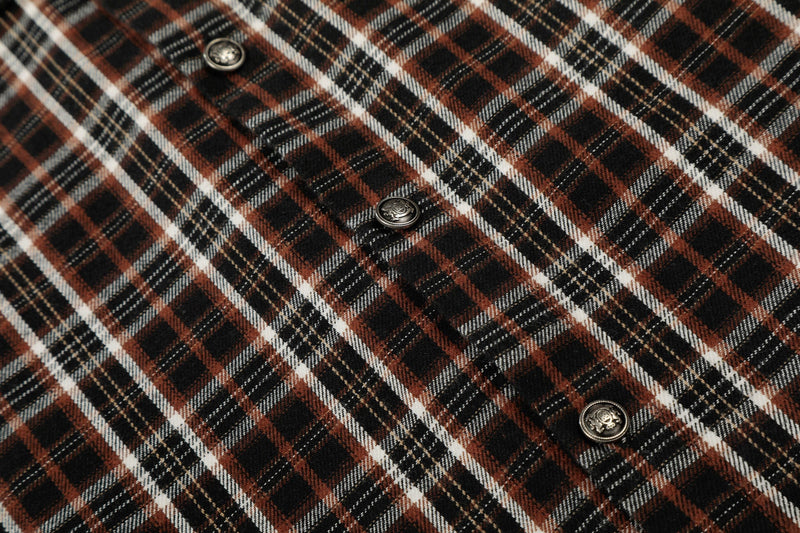 Close-up of a distressed brown, black, and white plaid shirt with metal buttons and raw-edge texture