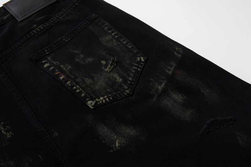 Close-up of back pocket on black denim jeans with paint-wash fading and distressing