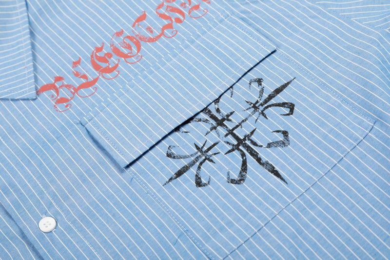 Close-up of blue striped shirt front pocket area with red lettering and black graphic print