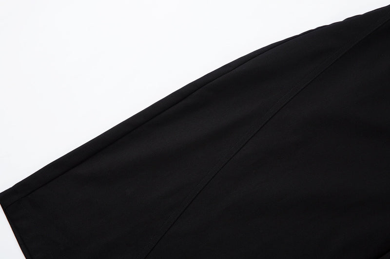 Close-up of curved outer seam running down the black pants leg