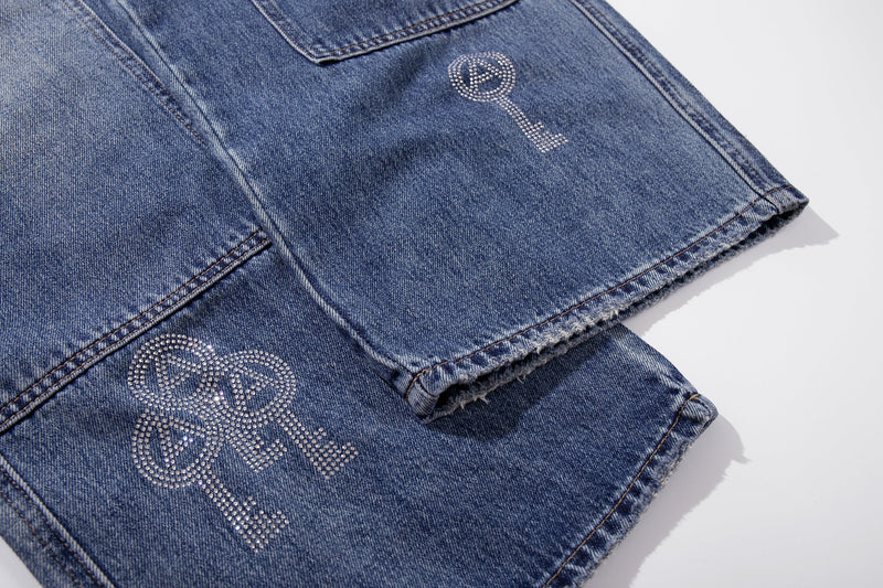Close-up of lower leg hem with rhinestone key design on blue denim jeans