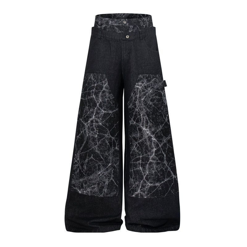 Front view of black wide-leg denim pants with cracked panel detailing and high waist
